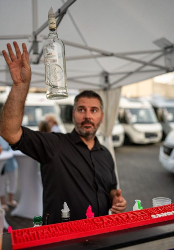 Barkeeper hebt eine Flasche Wodka in die Luft während der Zubereitung eines Cocktails.