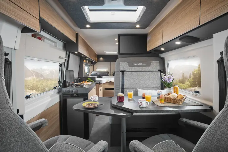 Innenraum eines Malibu Wohnmobils mit Sitzen, Tisch und Küche.