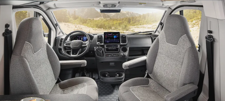 Innenansicht eines Campers mit zwei grauen Sitzen und einem Armaturenbrett.