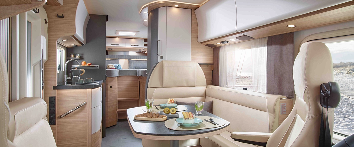 Innenansicht eines modernen Reisemobils mit einem komfortablen Sitzbereich und einem Tisch.