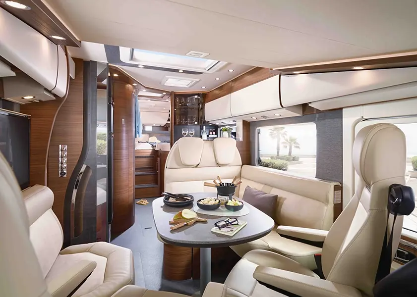 Eleganter Innenraum eines Wohnmobils mit einem Essbereich und komfortablen Sitzen in neutralen Farben.