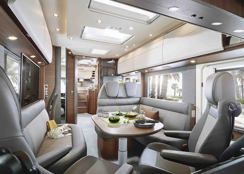 Moderne Wohnmobil-Innenausstattung mit Sitzgruppe, Tisch und hellem Ambiente.