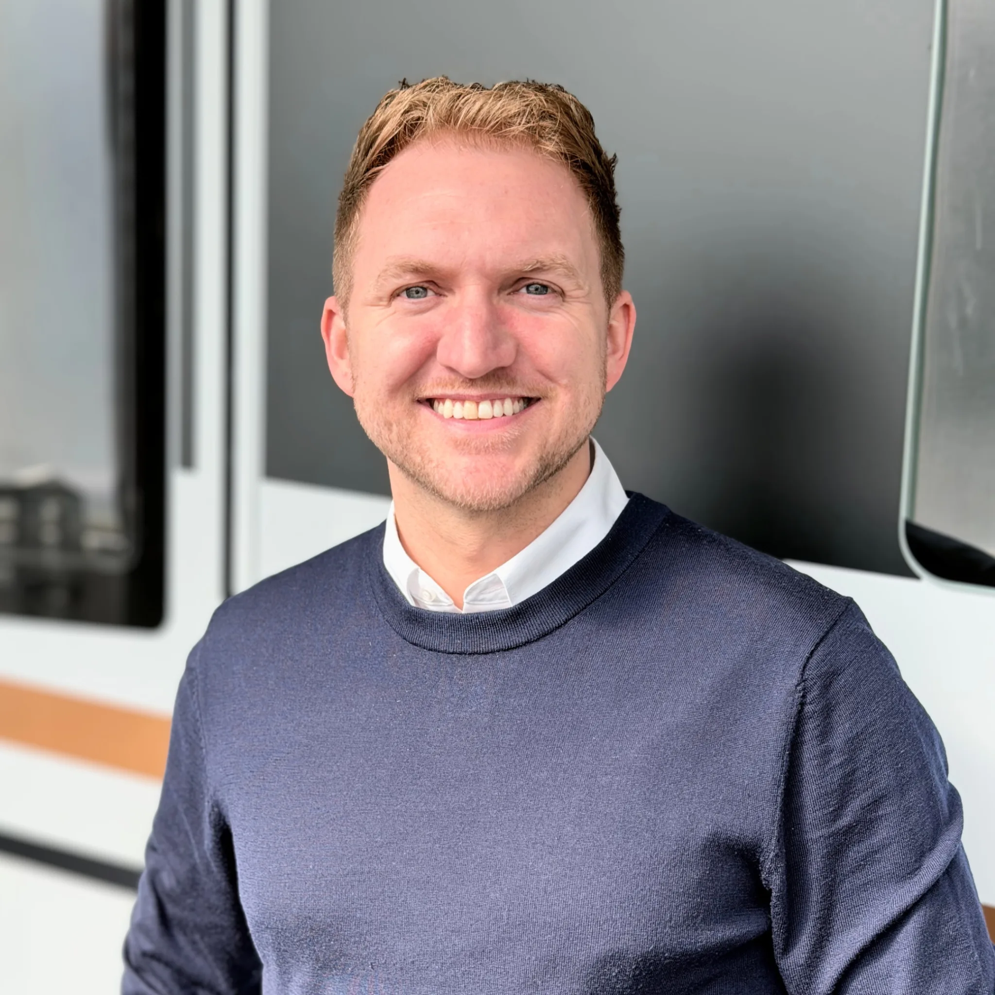 Ein freundlich lächelnder Matthias Kabok steht vor einem Malibu Camper Van und präsentiert das Malibu Center Köln bei Reisemobile Berens.